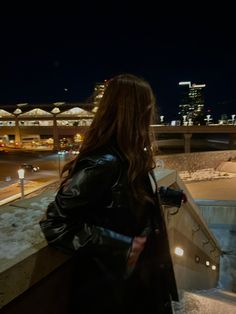 a woman standing on top of a bridge at night