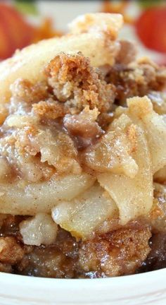 a close up of a bowl of food with apples in the background and an apple pie on top