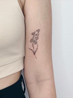 a woman's arm with a small flower tattoo on the left side of her arm