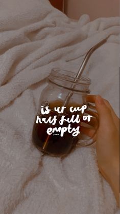 a person holding a jar with liquid in it on top of a white blanket and the words is us cup has fuel or empty