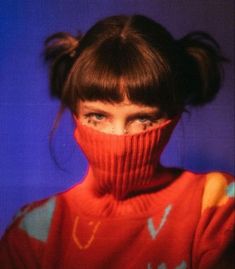 a woman wearing a red sweater and covering her face