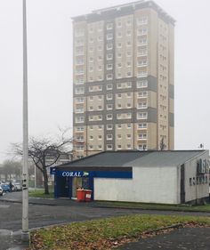 an empty parking lot in front of a tall building on a foggy, overcast day