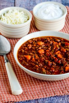 two bowls filled with chili and rice on top of a red checkered table cloth