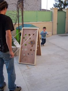 two young boys playing with a giant board game on the sidewalk in front of a building