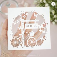 a person holding up a card with a bicycle on the front and flowers in the back