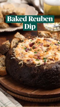 baked bread with cheese and other toppings sitting on a wooden platter next to silverware