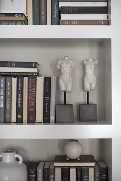 a book shelf with books and vases on it