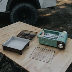 a green toaster sitting on top of a wooden table next to a metal pan