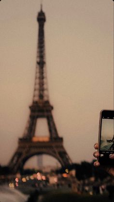 the eiffel tower is lit up at night with its lights on and people taking pictures