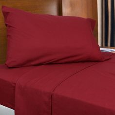 a bed with red sheets and pillows in a hotel room