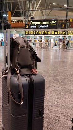 two pieces of luggage sitting on top of each other in an airport terminal with signs above them