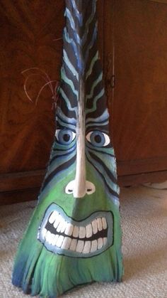 a green mask with black and white stripes on it's face is sitting in front of a wooden cabinet