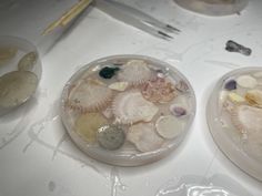 two plates filled with shells on top of a white countertop next to chopsticks and utensils