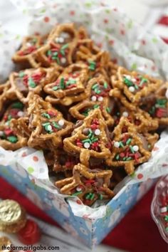 a box full of pretzels with sprinkles on them and some cookies in the background