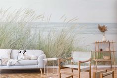 a white couch sitting on top of a wooden floor next to tall grass covered walls