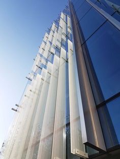 the side of a tall building with many windows on it's sides and sky in the background