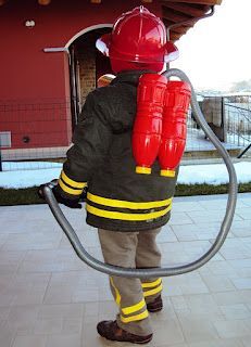 a fireman with a hose attached to his back standing in front of a building