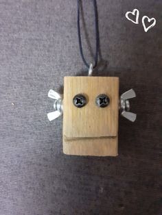 a wooden block with two black eyes and one white face hanging from a string on a carpet