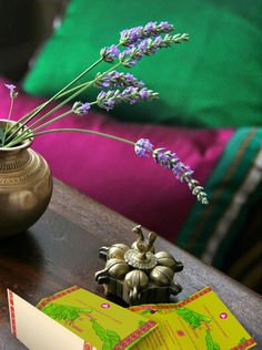 there is a vase with flowers on the table next to an open book and some cards