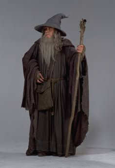 an old man dressed in costume and holding a staff with a hat on his head