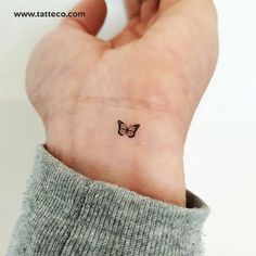 a small butterfly tattoo on the wrist is shown in black ink, and it has a tiny