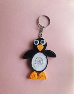 a black and white penguin keychain on a pink surface with an orange eye patch