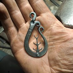 a person's hand holding an old metal hook