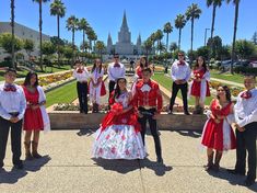 a group of people dressed in costumes posing for a photo outside with palm trees and buildings in the background