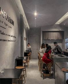 people sitting at tables in a restaurant with signs on the wall and chairs around them