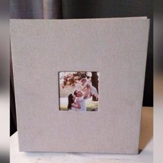 an open photo album with a couple holding a baby in it's lap and the cover is white