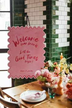 a sign that is on the wall near a table with plates and flowers in front of it