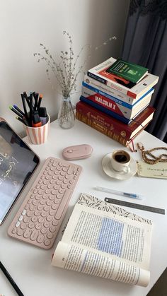 a table topped with books and a keyboard next to a cup of coffee on top of it