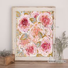 a painting with pink flowers on it sitting next to a wooden box and some plants