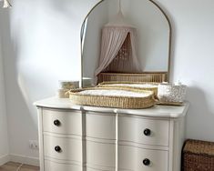 a baby crib sitting on top of a dresser next to a mirror