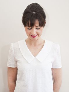 a woman wearing a white shirt and holding a cell phone