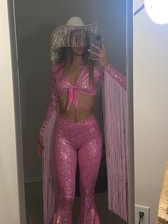 a woman in pink sequins taking a selfie with her cell phone while wearing a hat