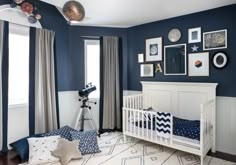 a baby's room with blue walls and pictures on the wall, including a crib