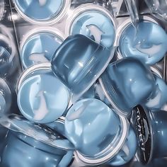 many blue cups are stacked together in a bin with lids and spoons on them