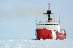 a large red and white boat floating on top of snow covered ground