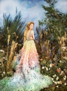 a woman in a dress made out of flowers and grass standing in the middle of a field