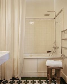 a white bath tub sitting under a window next to a sink and shower head mounted faucet