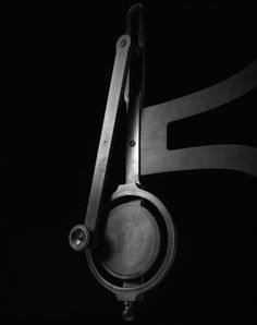 a black and white photo of a pair of scissors hanging from a hook on a wall