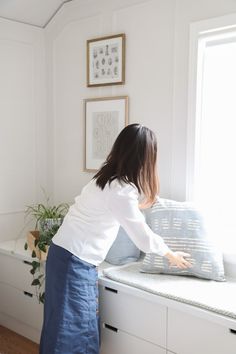 a woman standing on top of a window sill next to a white countertop