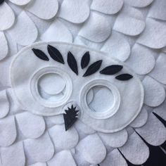 an owl made out of white felt with black leaves on it's face and eyes