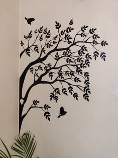 a tree with birds flying around it on the wall next to a potted plant