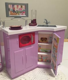 a toy kitchen with sink, stove and refrigerator in it's open door area