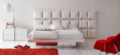 a white bedroom with red rugs on the floor and a bed in the middle