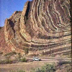 a truck is parked in front of a huge rock formation