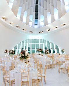 an indoor wedding venue with round tables and white linens