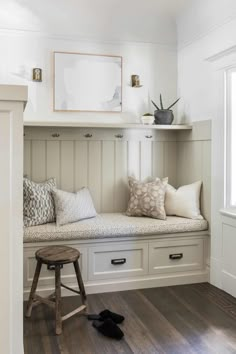 a window seat with pillows on it in front of a blue door and white cabinets